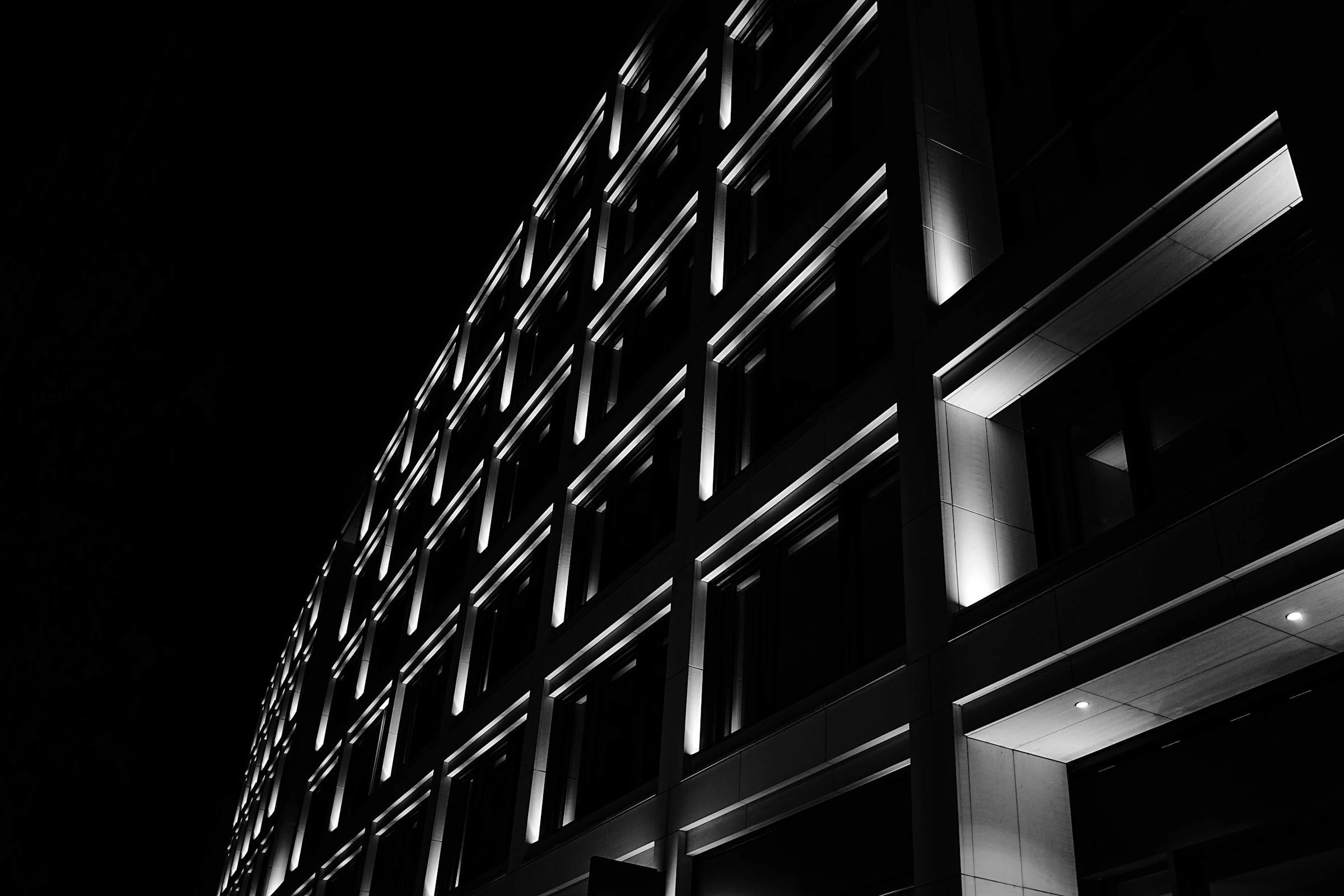 Dunkle Fassade eines modernen Bürogebäudes bei Nacht